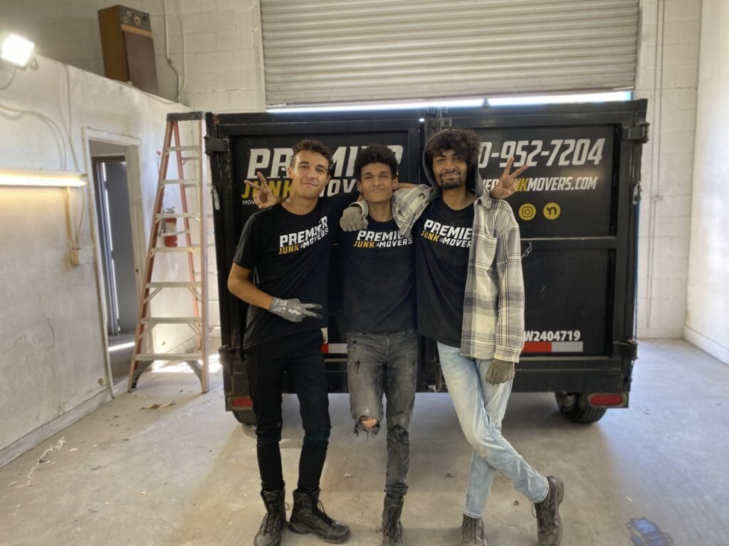 Premier Junk Movers crew in front of a branded dumpster